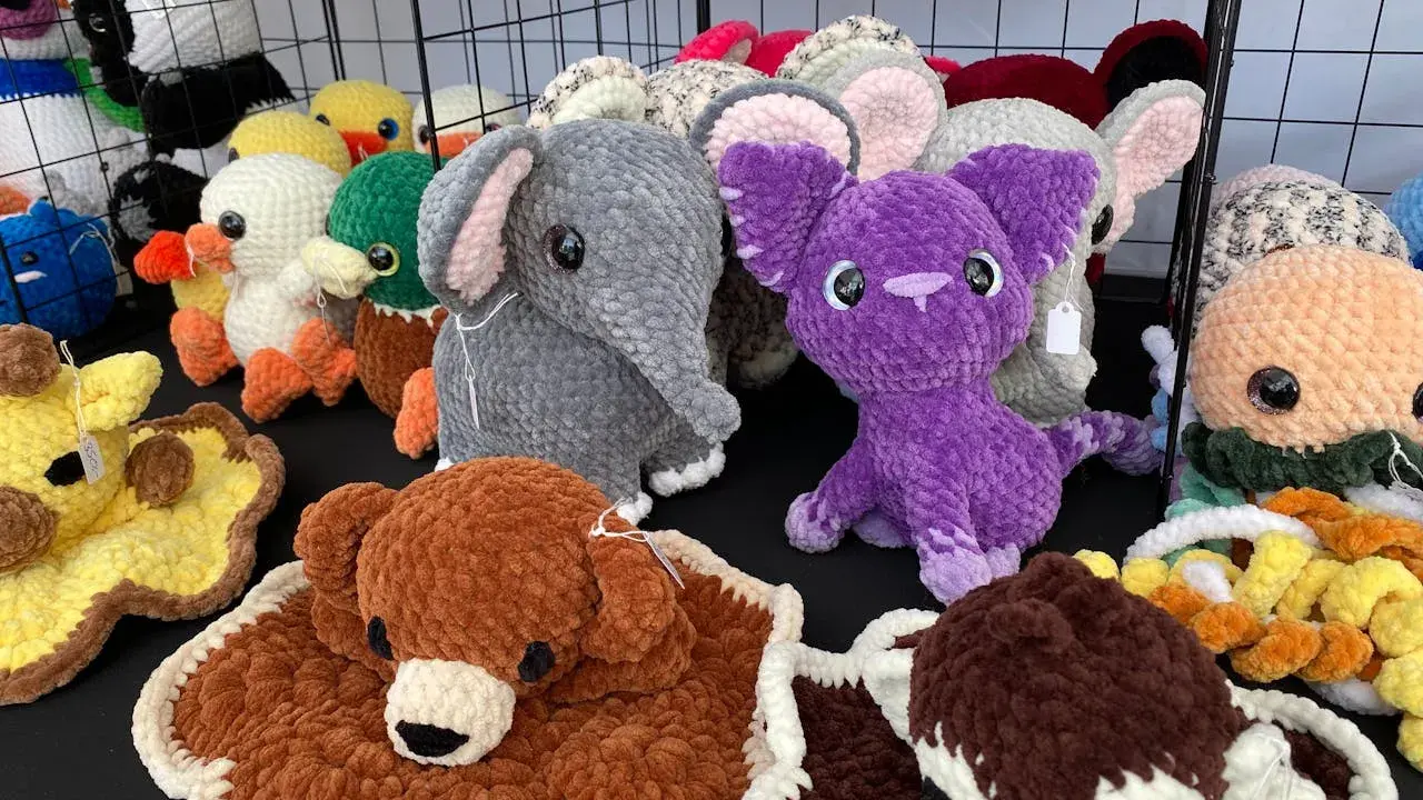 A variety of colorful, crocheted stuffed animals including elephants, ducks, a giraffe, and a purple creature.