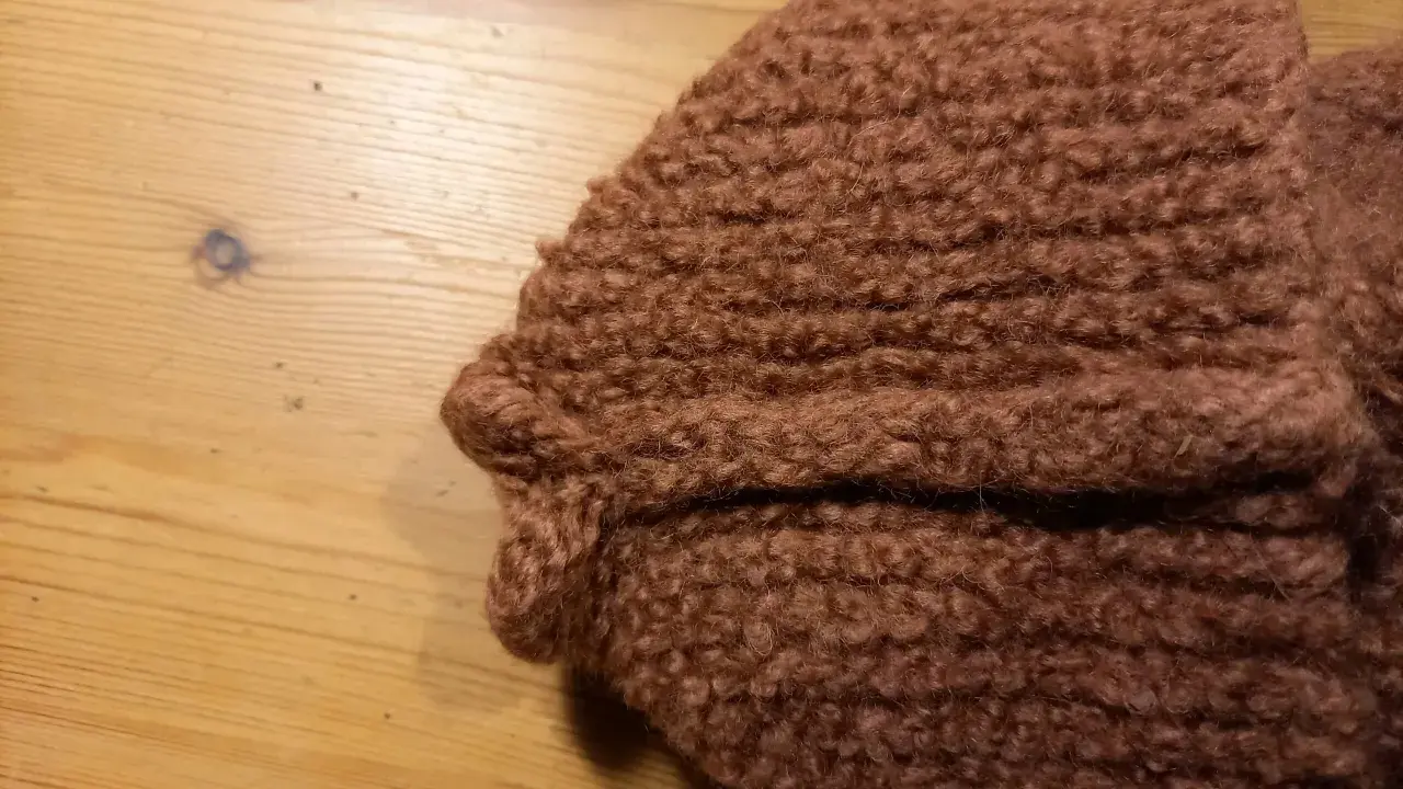 Bruna, sticka tovade tofflor ligger på ett träbord.