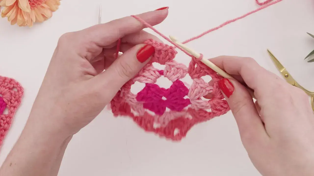 Händer virkar ett rosa virkat zigzag filt mönster med en virknål.