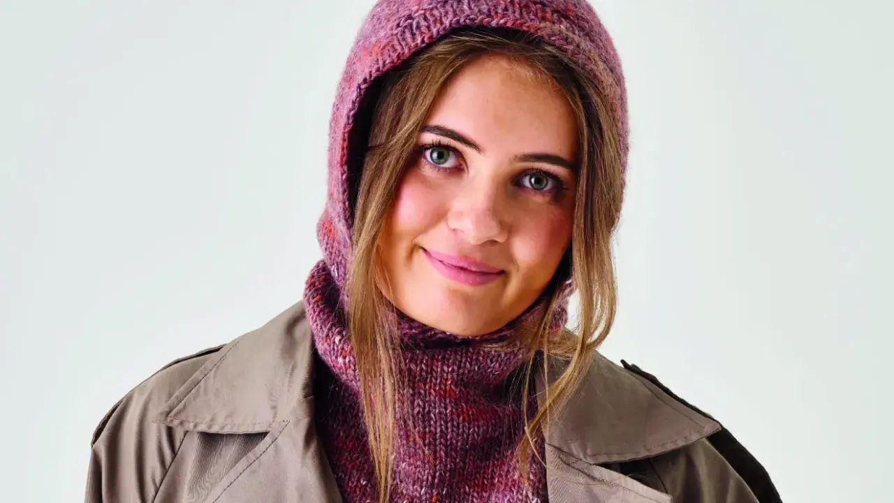 Ung kvinna med stickad balaclava i rosa toner och en beige kappa. Perfekt för barn som vill sticka en egen balaclava.