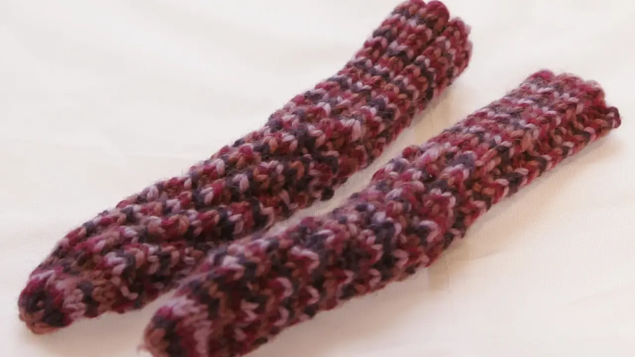 Två handstickade drops spiralsockor i ett melerat garn i vinröda och lila toner.