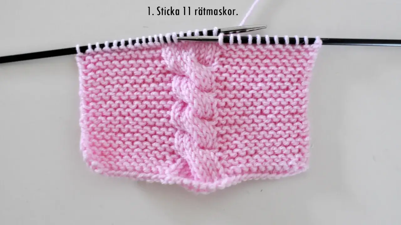 Rosa stickat tyg med flätmönster, perfekt för att sticka en disktrasa i land.