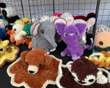 A variety of colorful, crocheted stuffed animals including elephants, ducks, a giraffe, and a purple creature.
