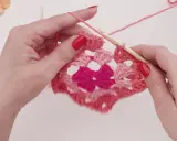 Händer virkar ett rosa virkat zigzag filt mönster med en virknål.