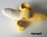 En virkad banan med skalet delvis avdraget. Den vita delen är bananen, och det gula är skalet.