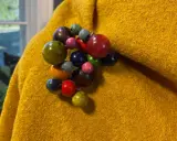 En gul, ullig poncho med en klunga av färgglada träpärlor som en brosch. Perfekt för att sy en unik poncho.