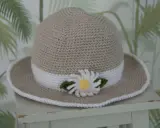 En virkad solhatt för barn, beige med vit kant och en söt blomdekor. Perfekt för soliga dagar!