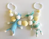 Crocheted giraffes with white and yellow beads hanging from white plastic rings.