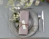 Vacker dukning med linneservetter, blommor och en korg med bröd. Perfekt för en sommarfest.