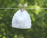 Vit virkad mössa med popcornmaskor hänger på en lina.