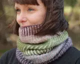 Woman wearing a colorful knitted cowl in shades of green, pink, and purple.