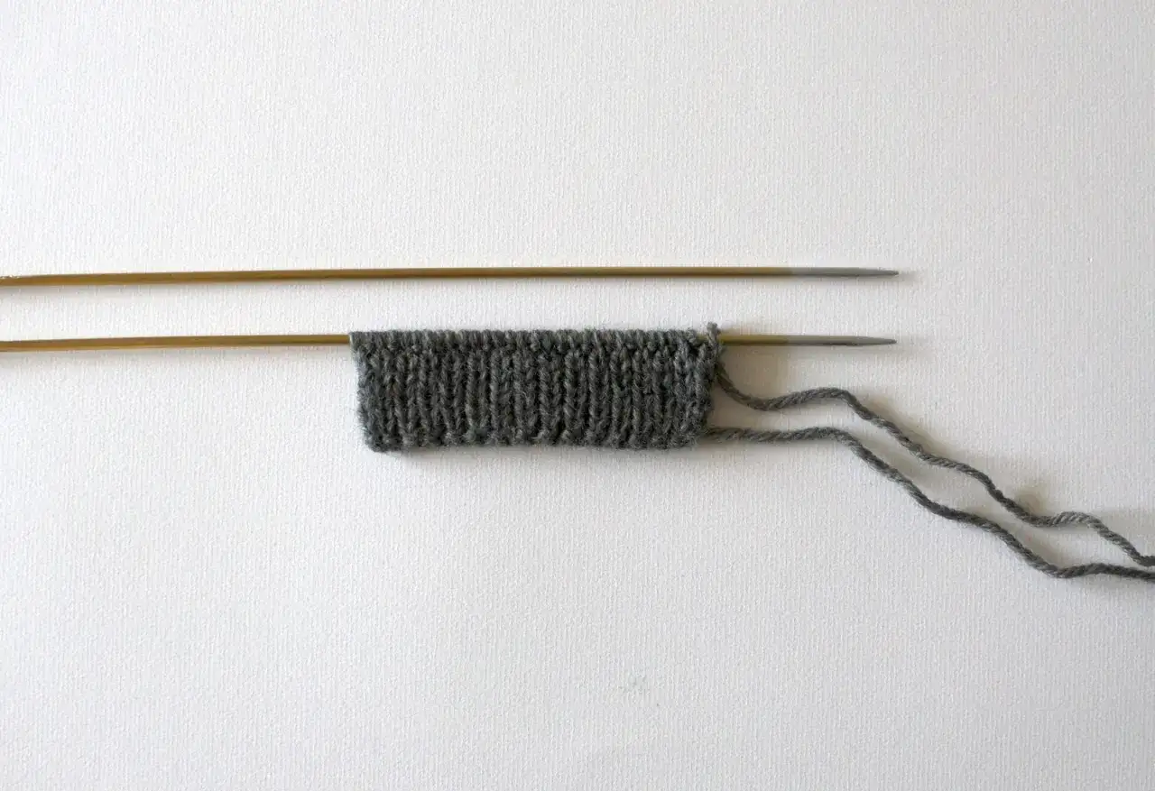 Grå stickning på stickor, redo att sticka vantar barn.
