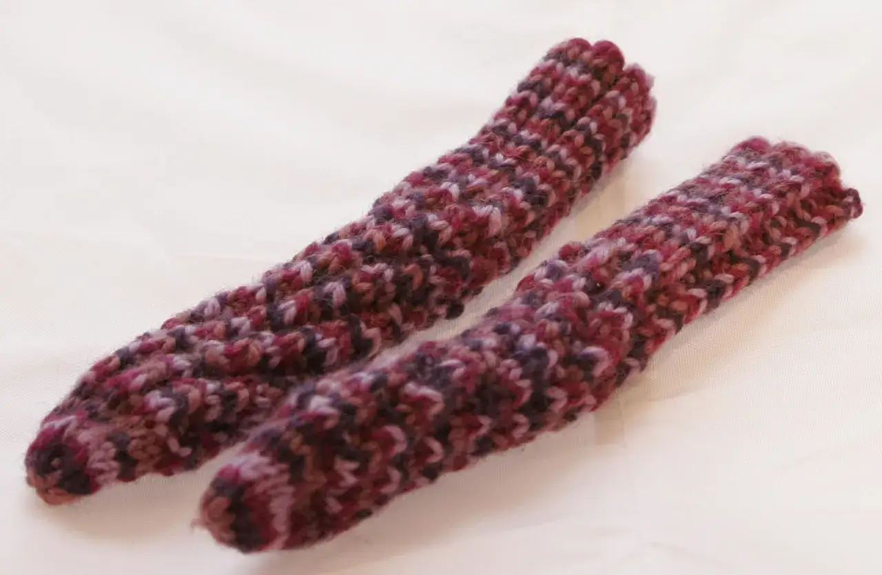 Två handstickade drops spiralsockor i ett flerfärgat garn med lila och vinröda toner.
