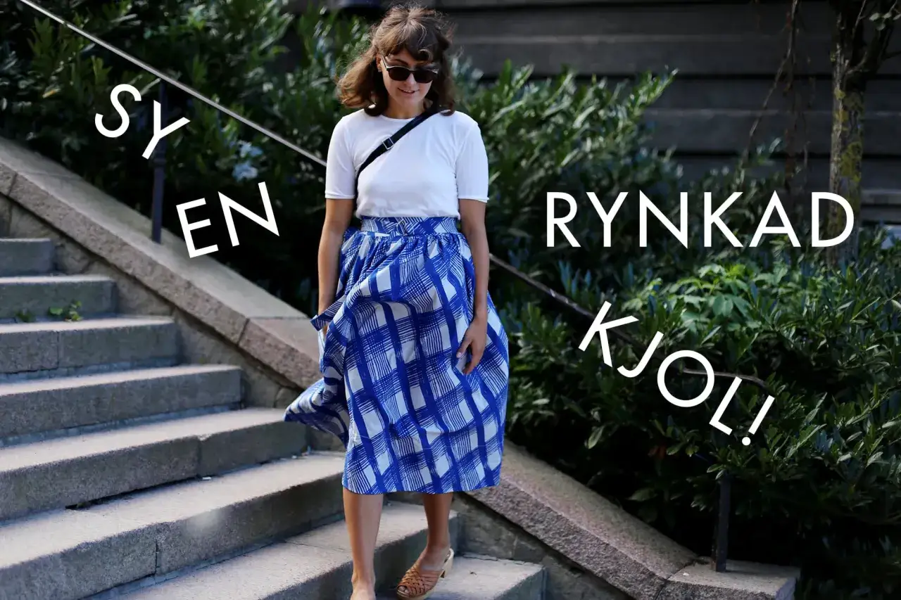 En kvinna g&aring;r nerf&ouml;r en trappa i en rynkad kjol i trik&aring; med bl&aring;tt rutm&ouml;nster.